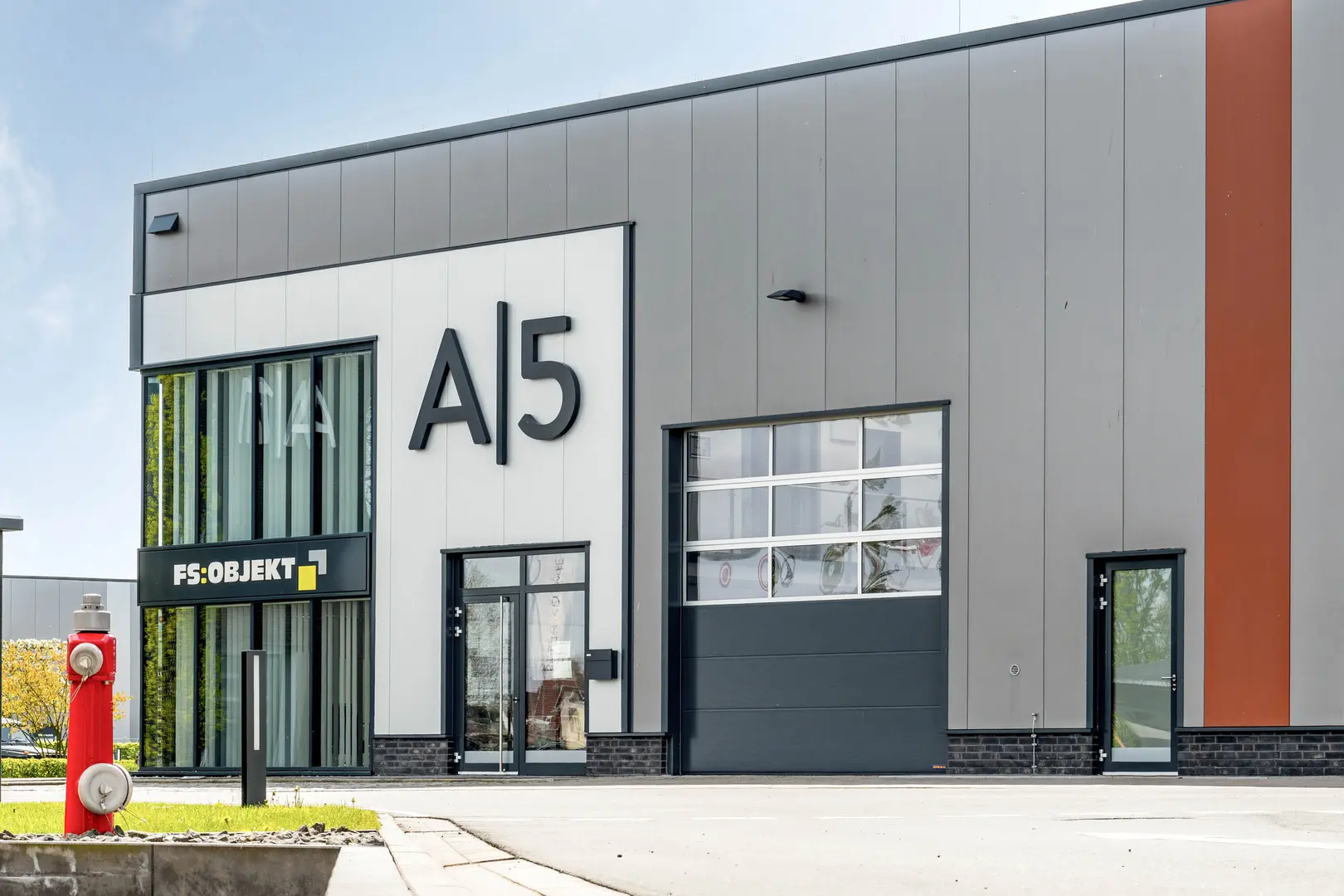 Foto der Halla A5 des Allerkai. Dargestellt ist eine große Halle mit einer großen Halbverglasten Garage und einer großen Glaseckfront.