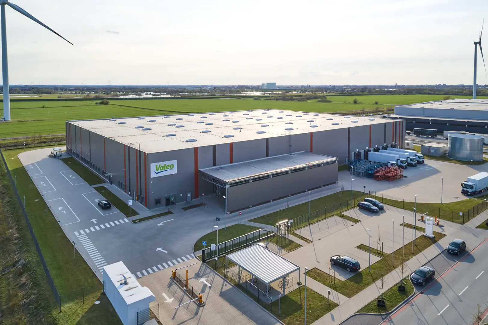 Luftaufnahme der Lagerhalle Hansalinie Bremen - Valo. Dargestellt ist eine große Lagerhalle mit überdachtem Vorbau für die Lagerung sowie ein gesicherter Parkplatz.